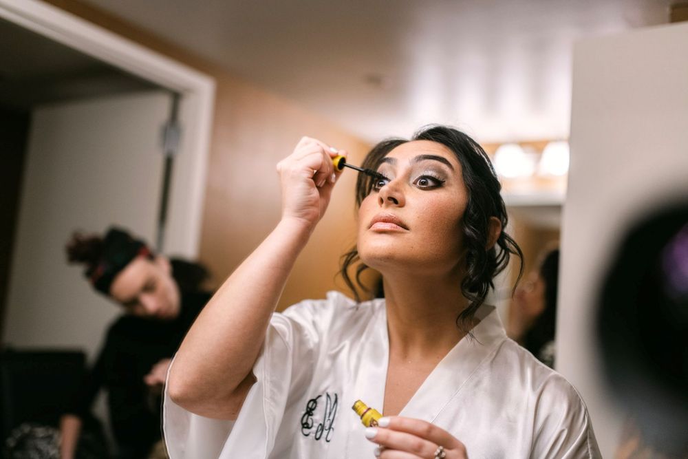Professional makeup artist applies cosmetics to model's face during beauty session in studio setting.