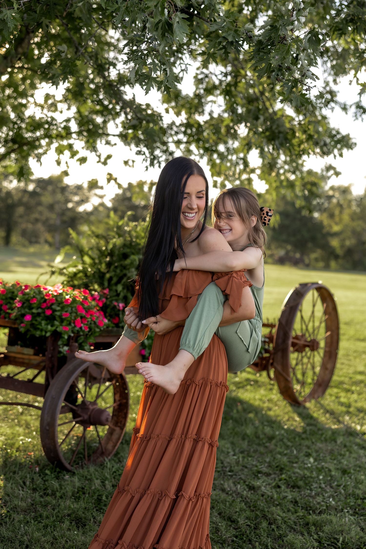 Two people in casual dress share joyful moments together in a garden setting with blooming flowers at sunset.