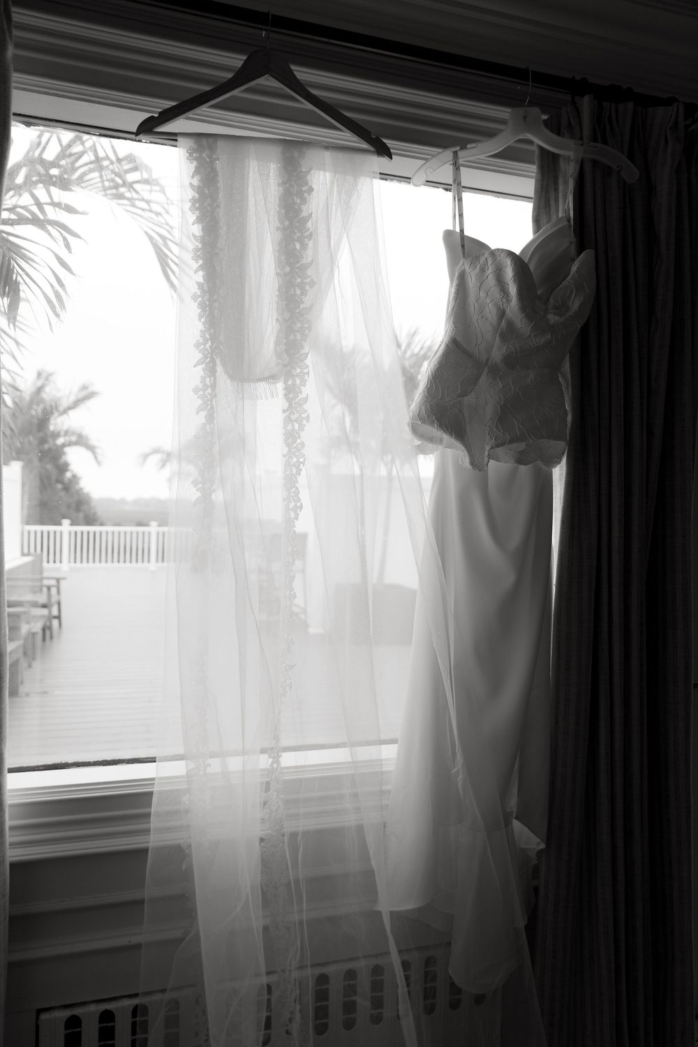 Wedding dresses hang in a row by windows, creating an ethereal silhouette against natural light.