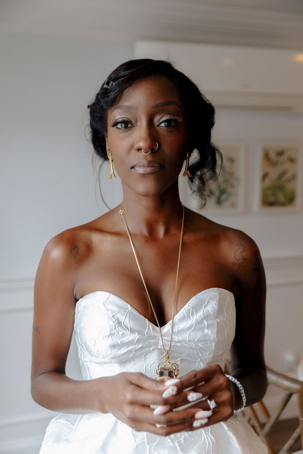 A bride in a white strapless gown holds a perfume bottle while getting ready for her wedding day.