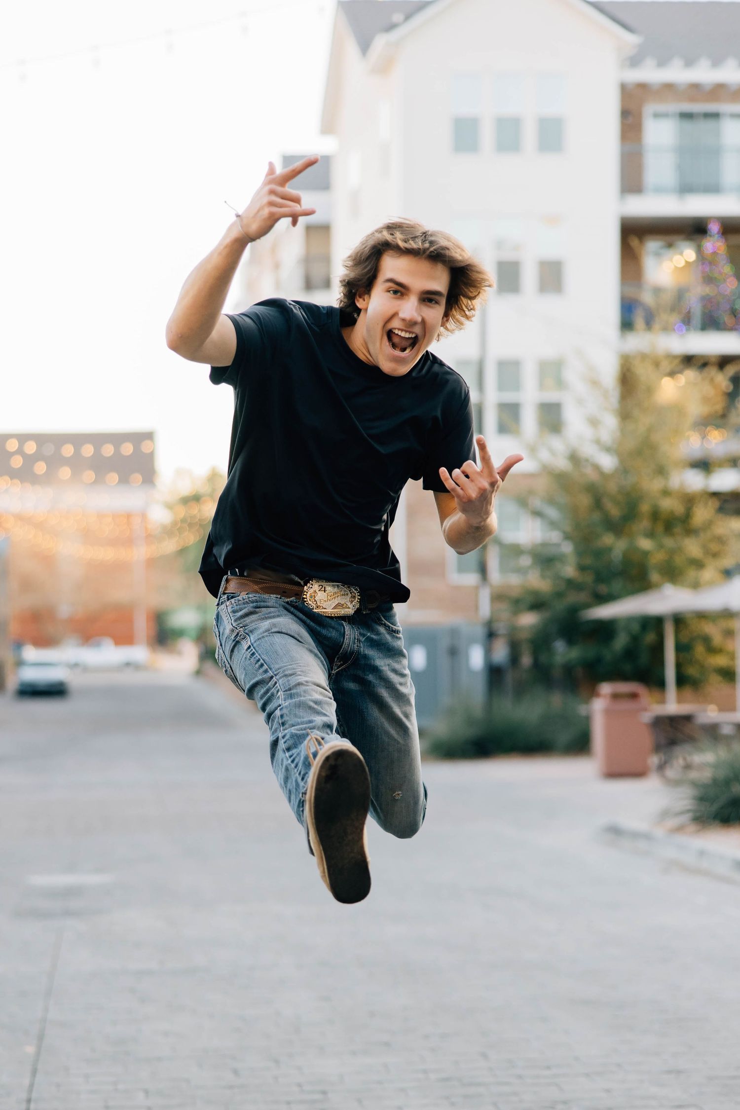 Energetic young man jumping in urban street wearing black t-shirt and jeans.