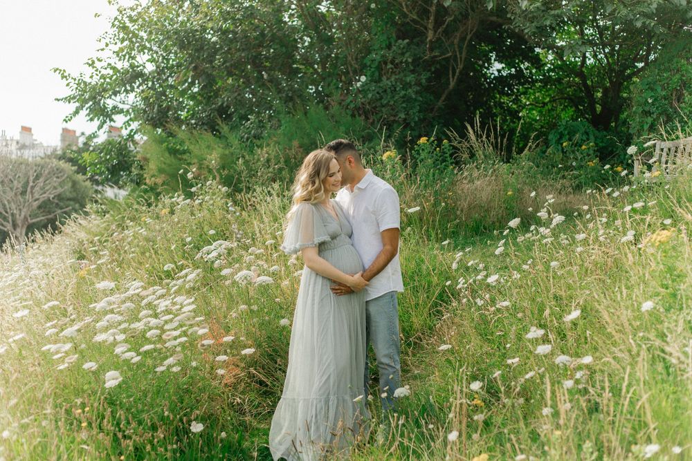 Romantic maternity photo of couple embracing in a wildflower meadow.