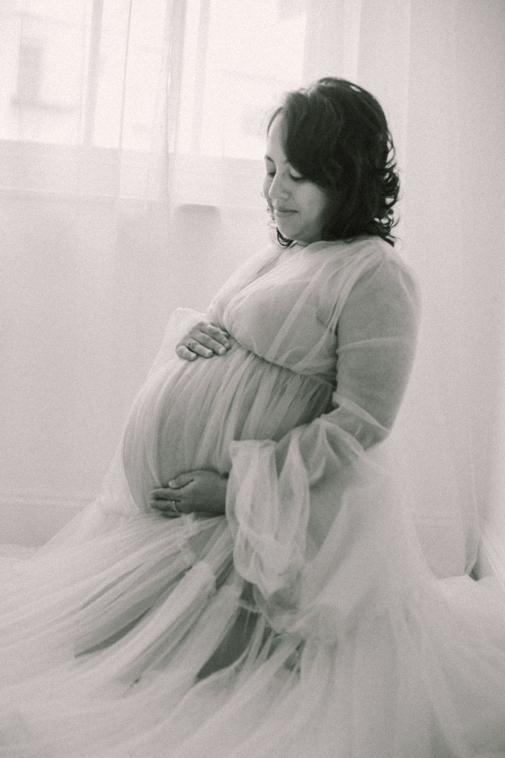 Dreamy black and white maternity portrait featuring a flowing white dress.