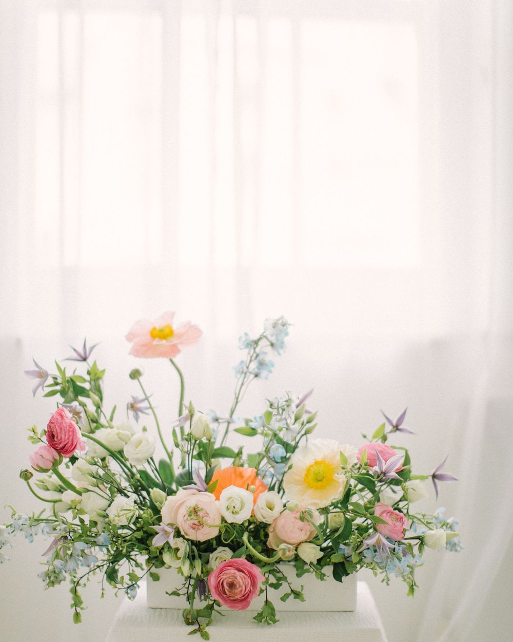 Colorful spring floral arrangement with roses, poppies and delicate greenery.
