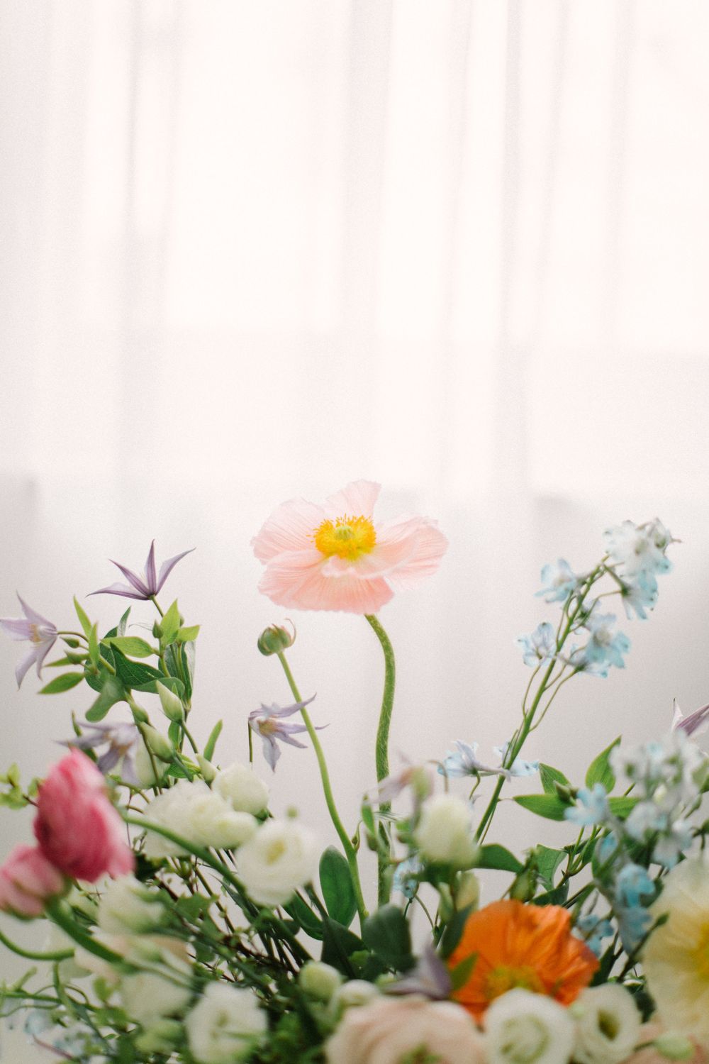 Close-up of dreamy spring flower arrangement with pink, orange and blue blooms.