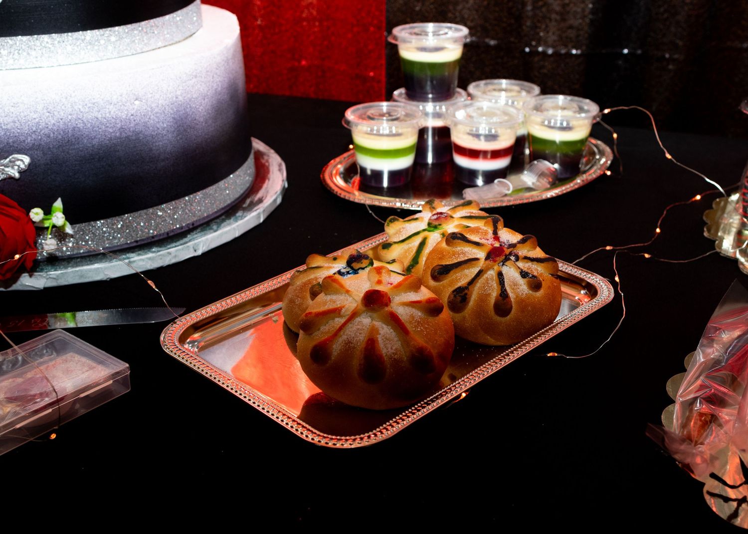 Assorted sushi rolls and sashimi arranged on black plates with garnishes in a dramatic dark lighting setting.