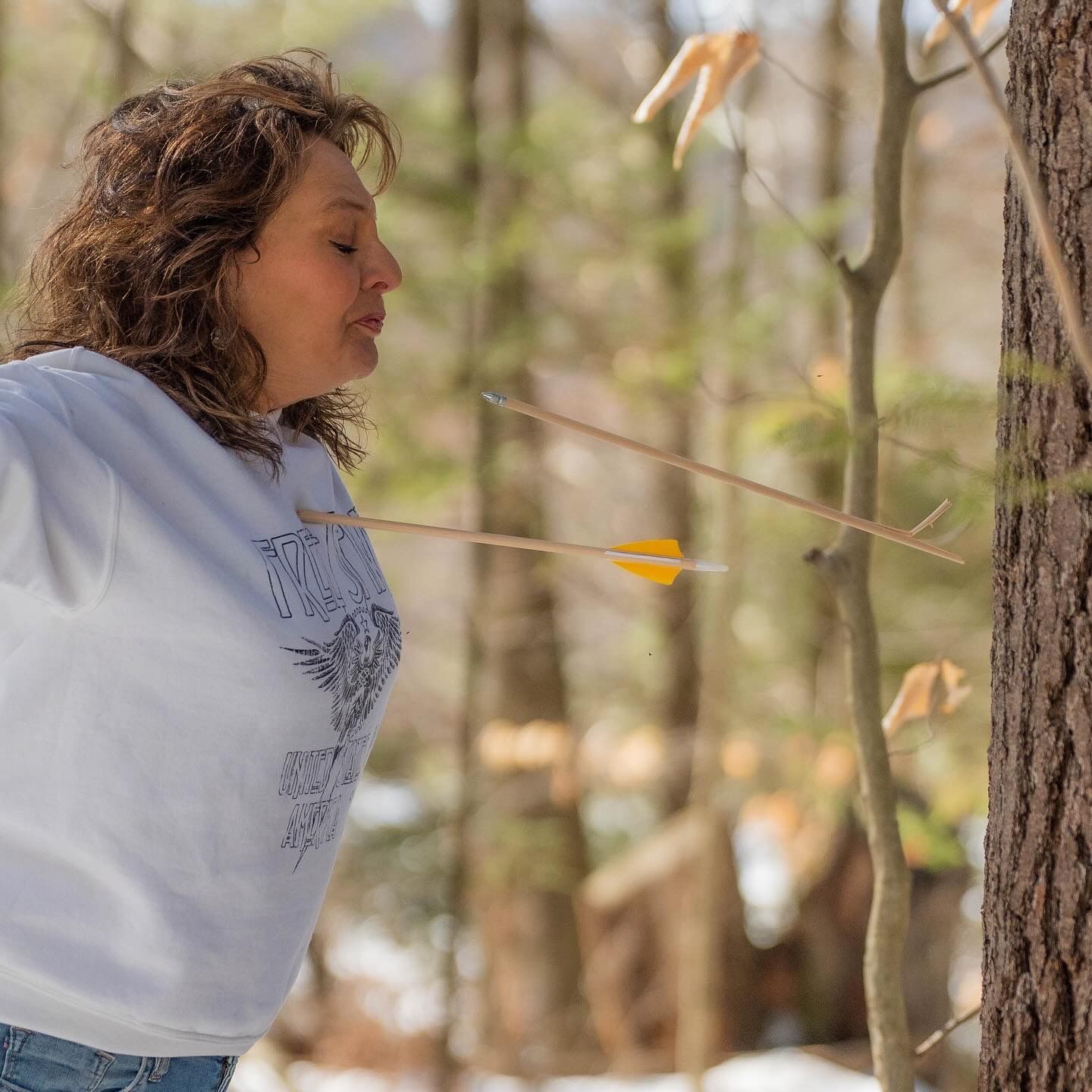 Casual outdoor photoshoot among trees with natural lighting and denim outfit.