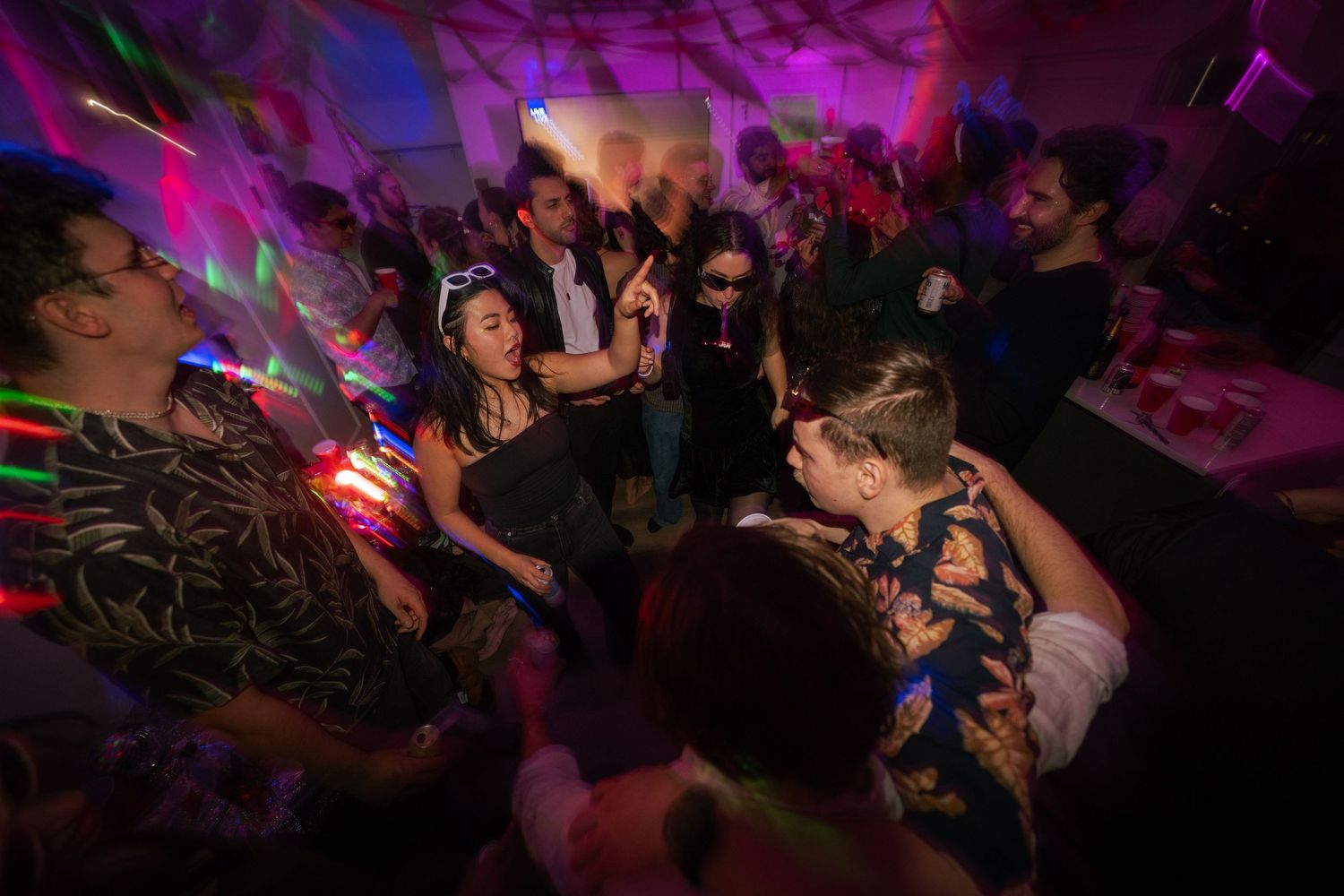 Energetic crowd dancing under colorful lights at a lively indoor party.