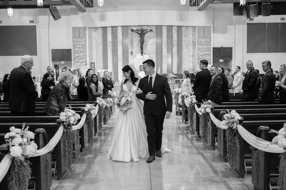 Church wedding ceremony with decorated pews and guests in attendance.