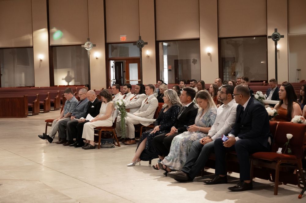 Wedding ceremony guests seated in rows of wooden pews inside a traditional church sanctuary.
