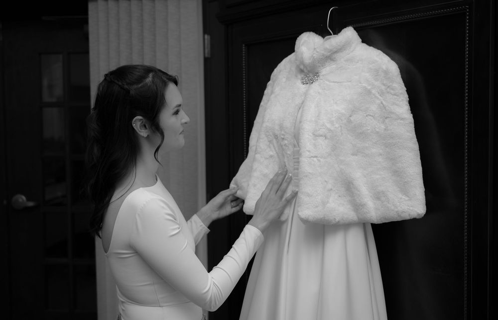 White fur bridal cape and wedding dress being prepared on display.