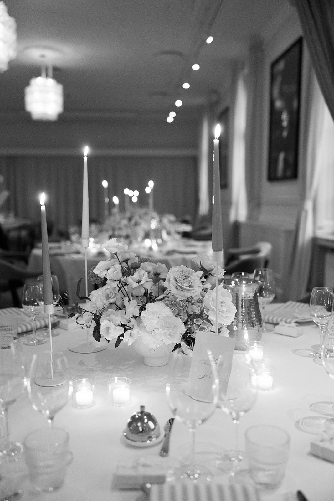 Elegant black and white wedding reception table setting with floral centerpiece, taper candles and crystal glassware.