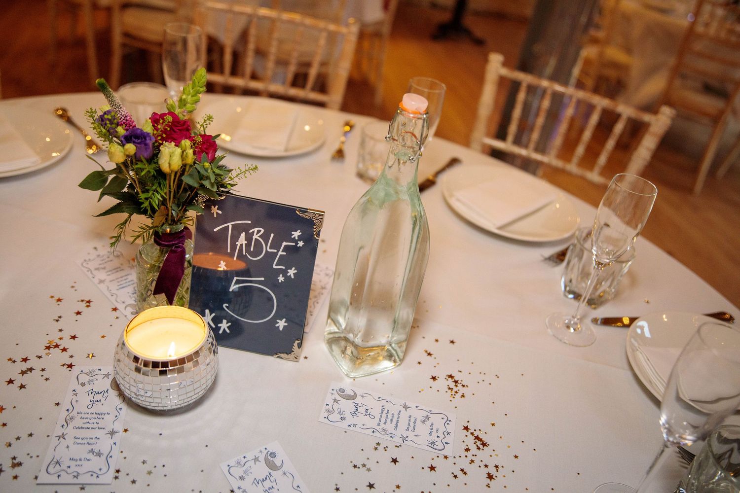 Elegant table settings with candles and floral centerpieces at a wedding reception.