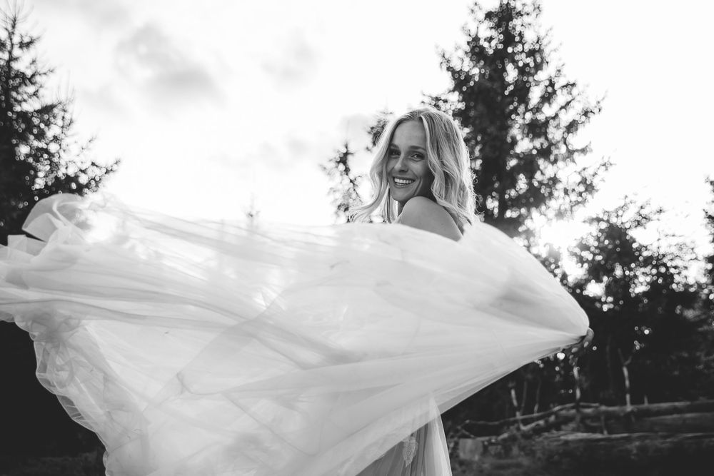 Flowing white dress catches wind during romantic outdoor photoshoot.