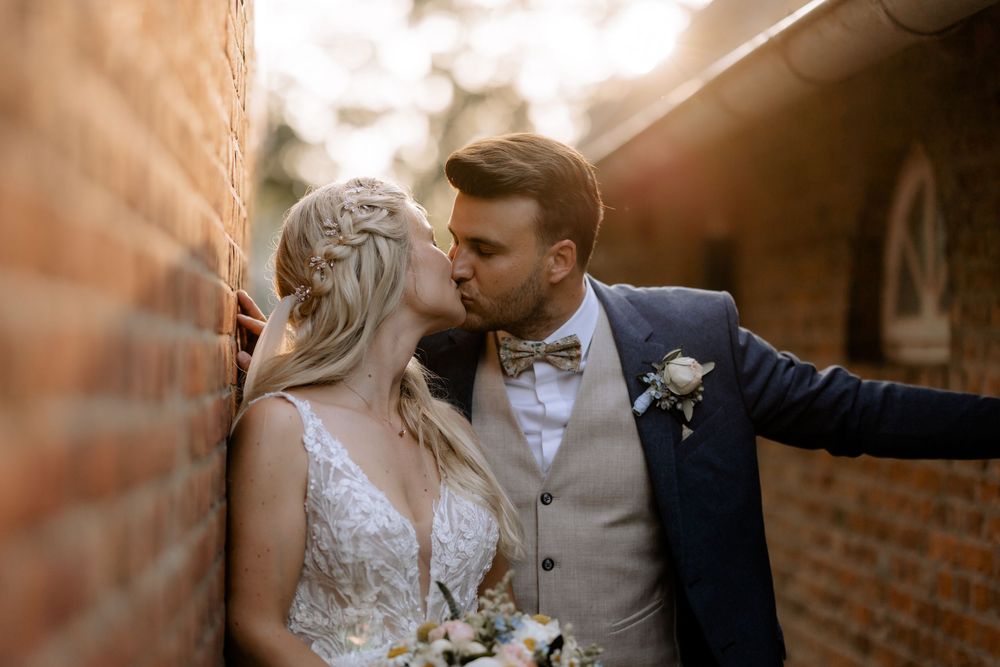 Romantic wedding portraits with warm lighting against brick wall backdrop.