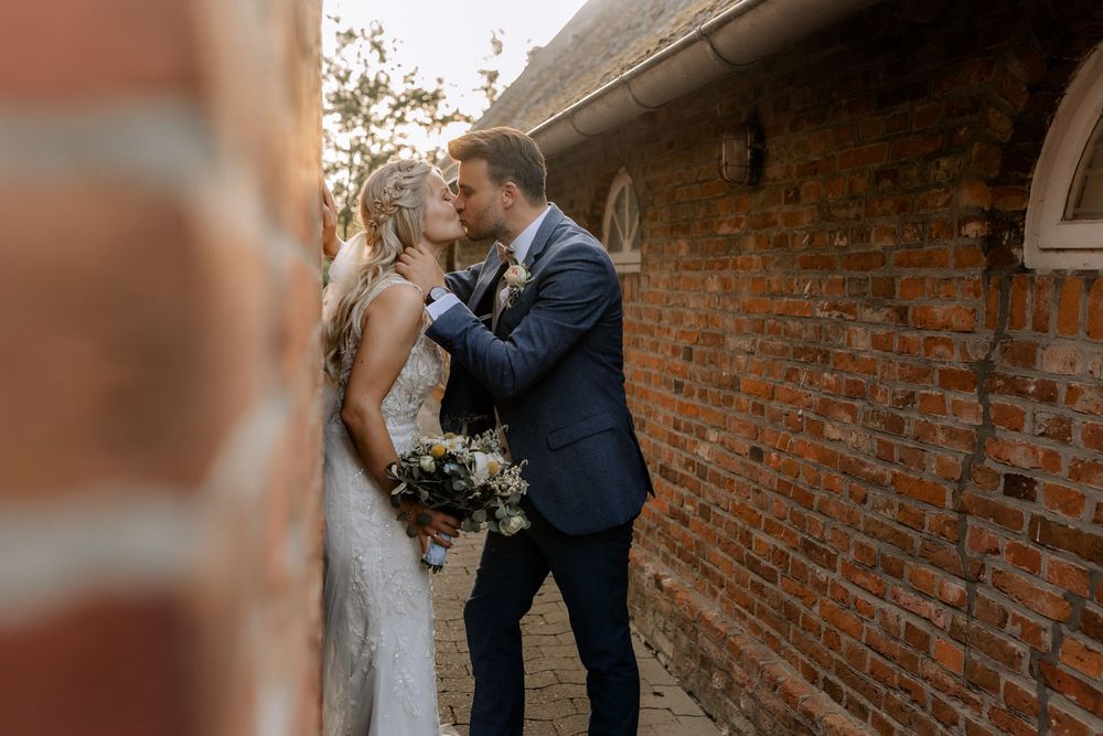 Intimate wedding moments captured against rustic brick architecture.