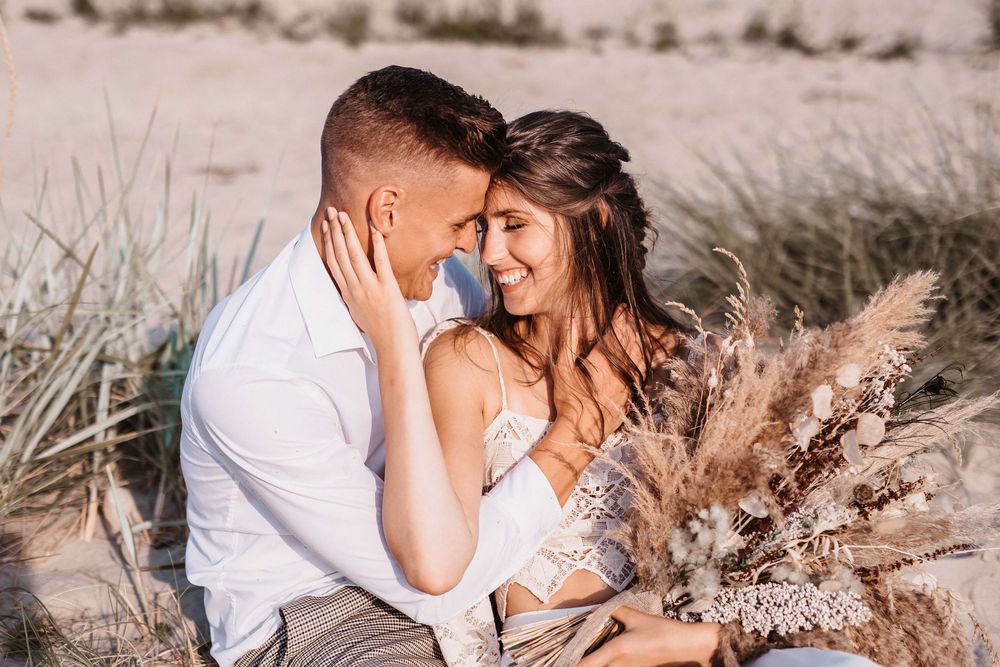 Romantic beach photoshoot with couple embracing in soft lighting.