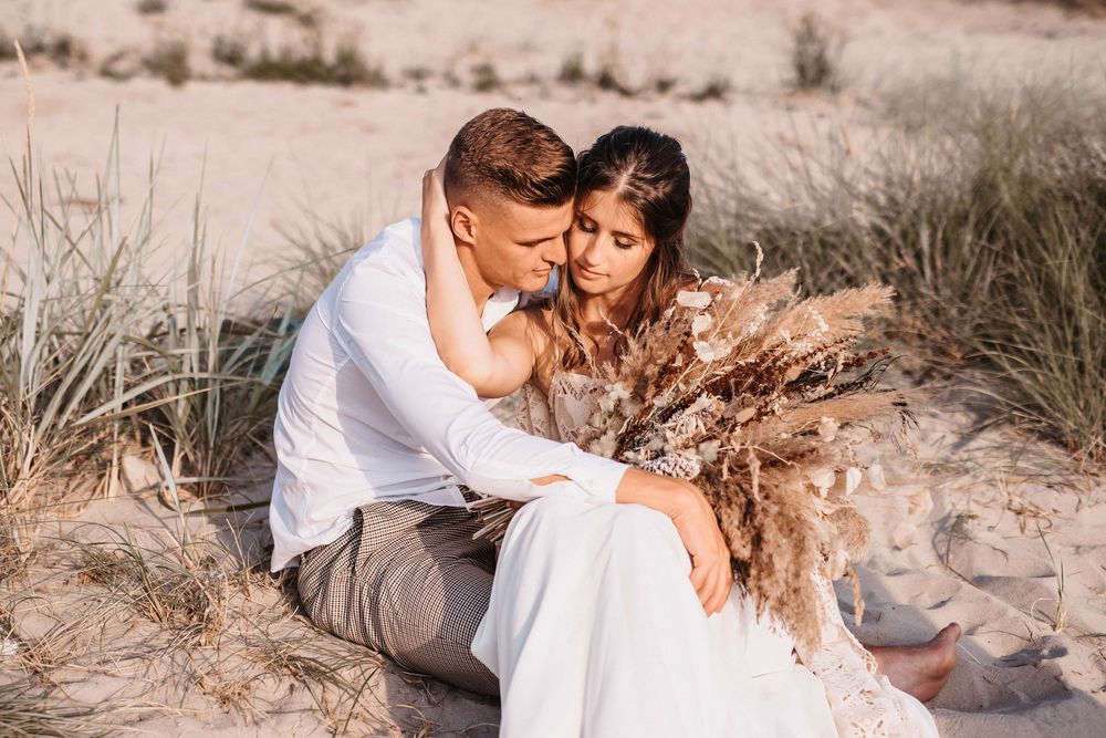 Intimate beach portraits with couple in white and neutral tones against sand dunes.