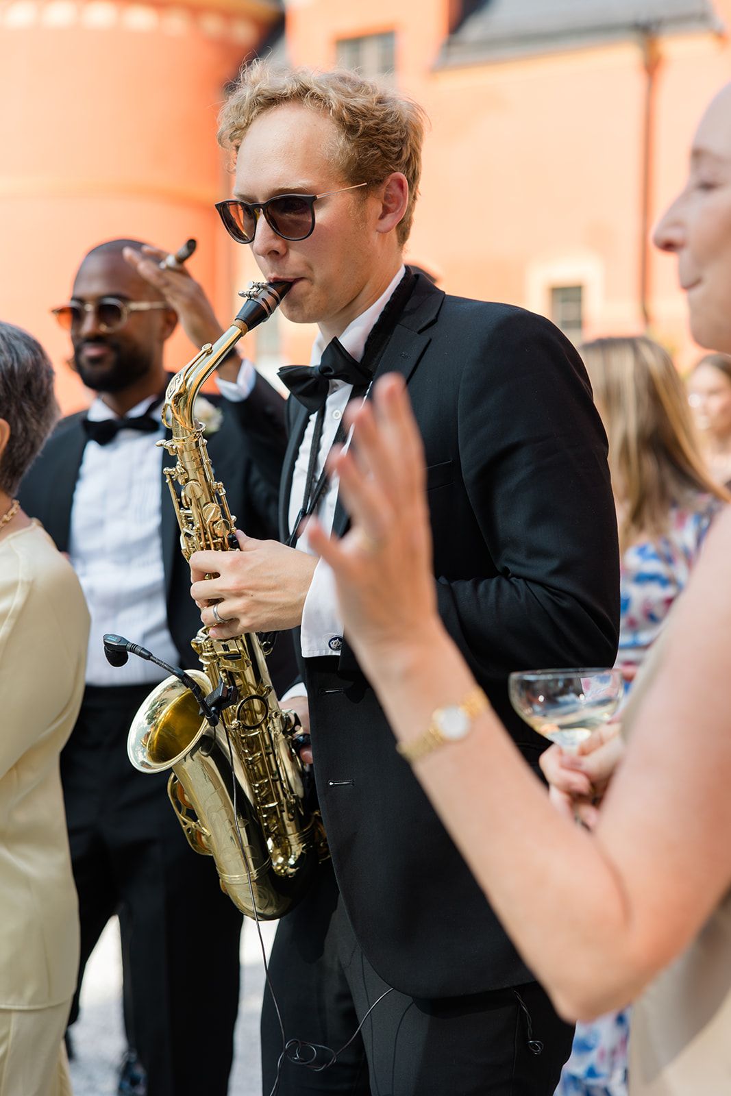 Musicians in formal attire perform with saxophones at an elegant outdoor event.