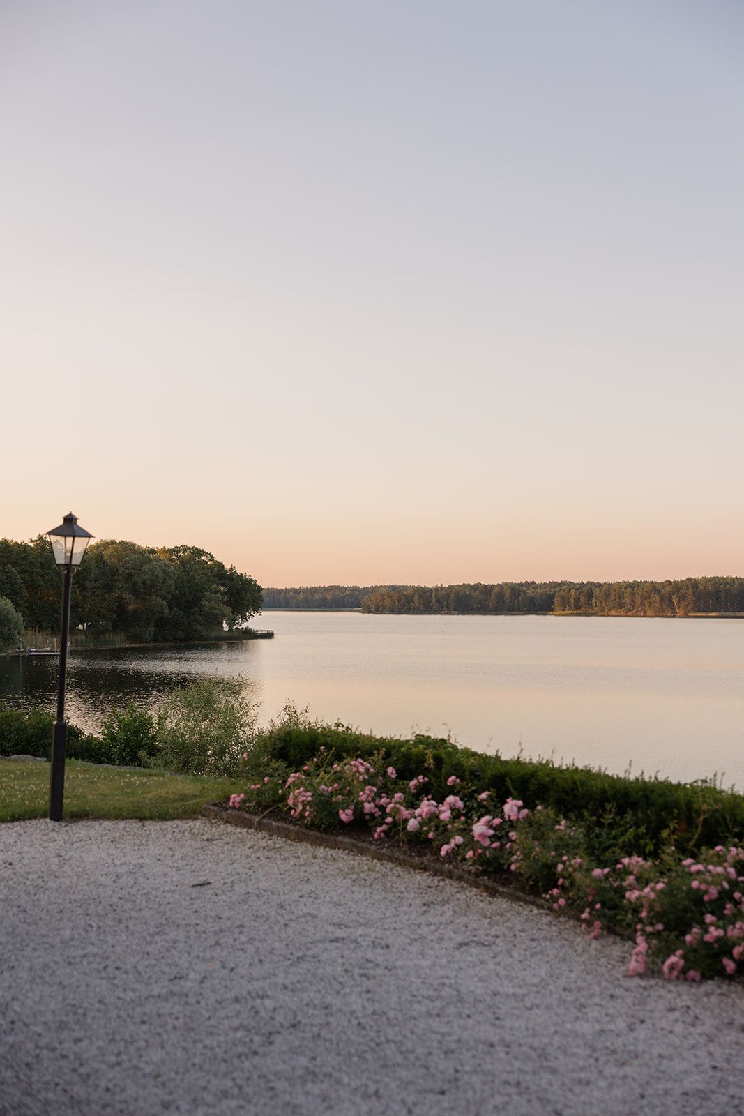 A couple in wedding attire embraces during a romantic sunset photoshoot in a park setting.