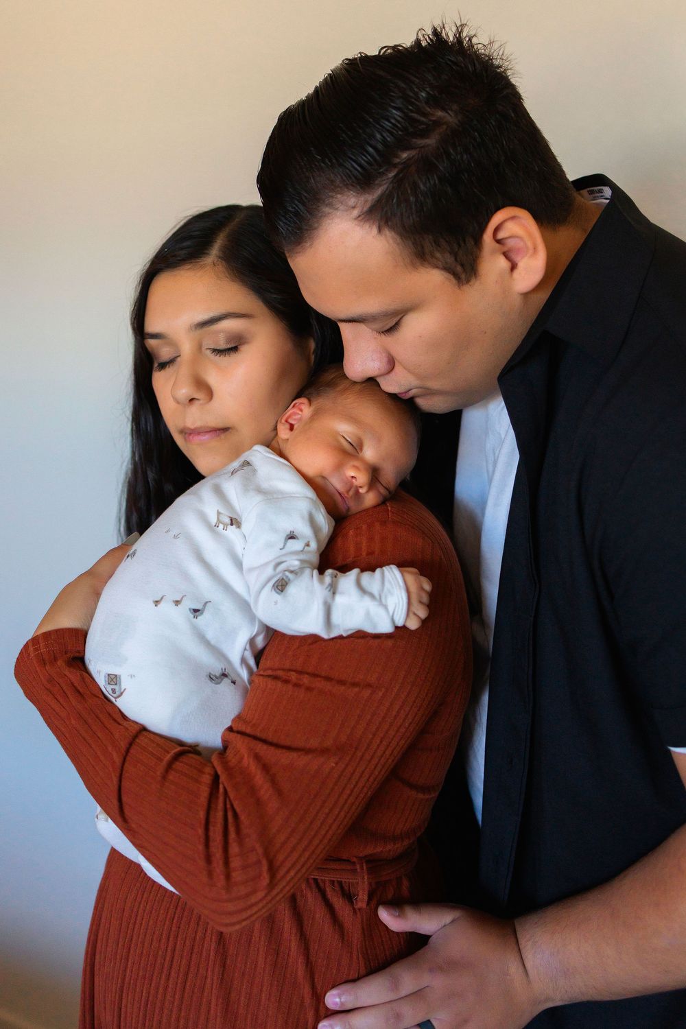 A series of tender moments showing a mom holding newborn baby on her chest.  Dad is leaning over and kissing babys head