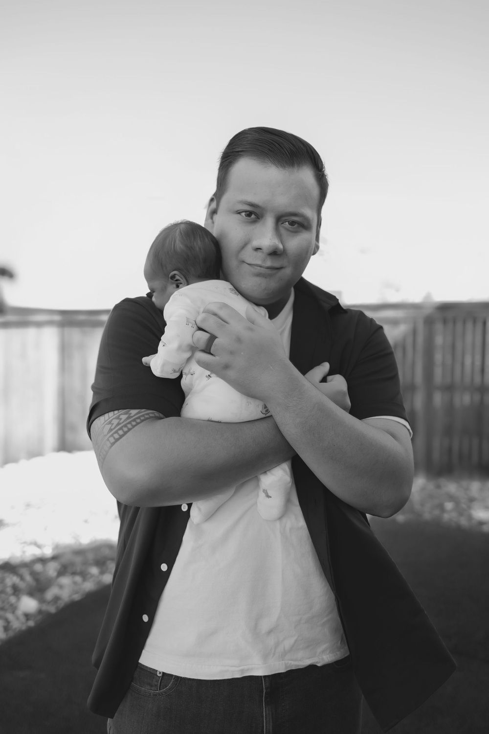 Man holding a newborn baby, he is looking at the camera, black and white image