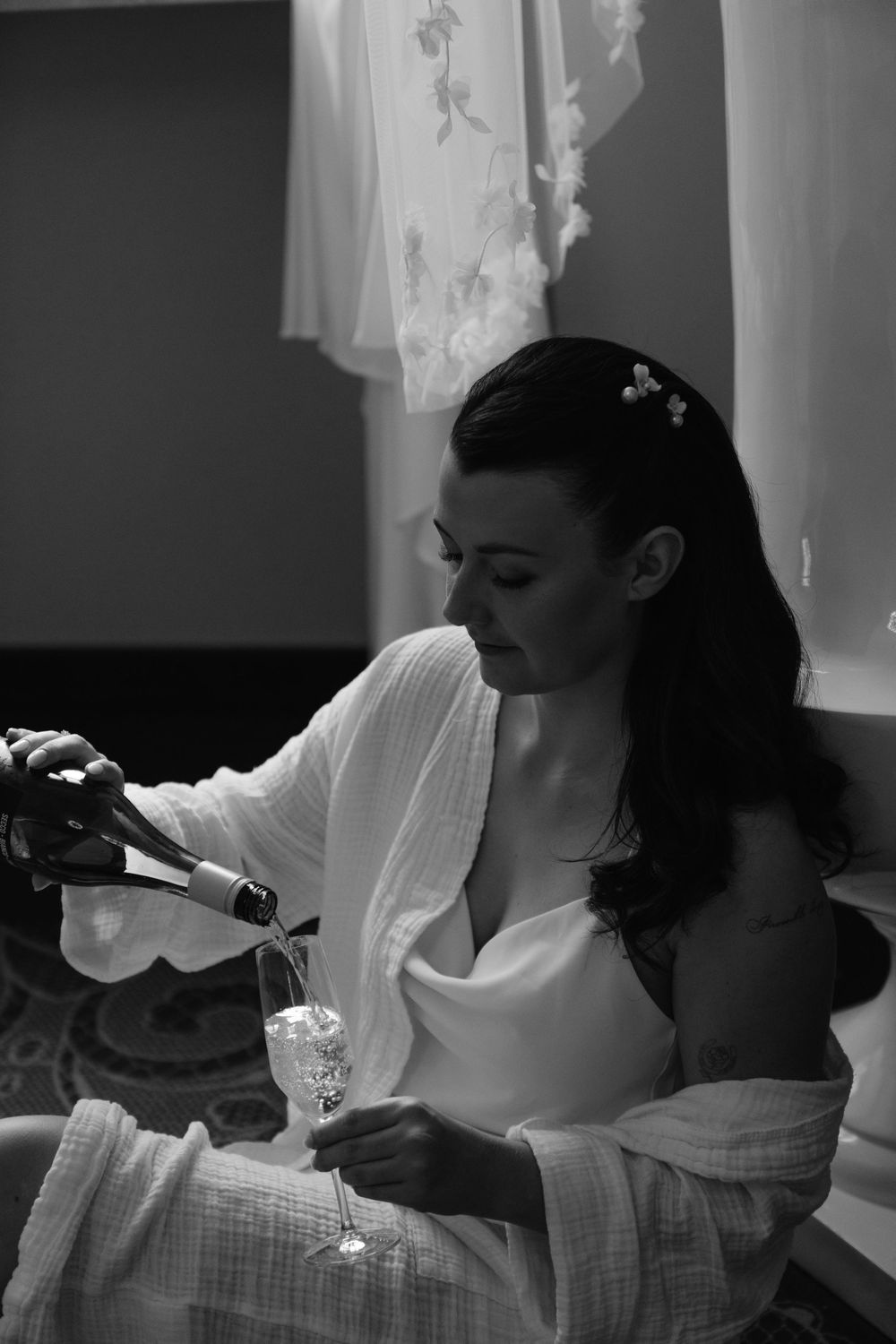 Black and white sequence showing a bride getting ready while drinking from a champagne bottle.