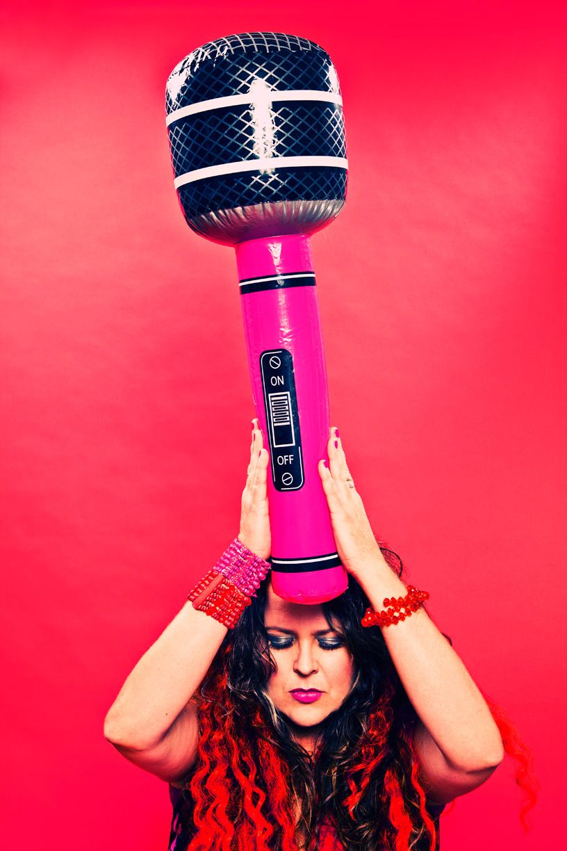 A pink microphone held against a vibrant red background in a playful pose.