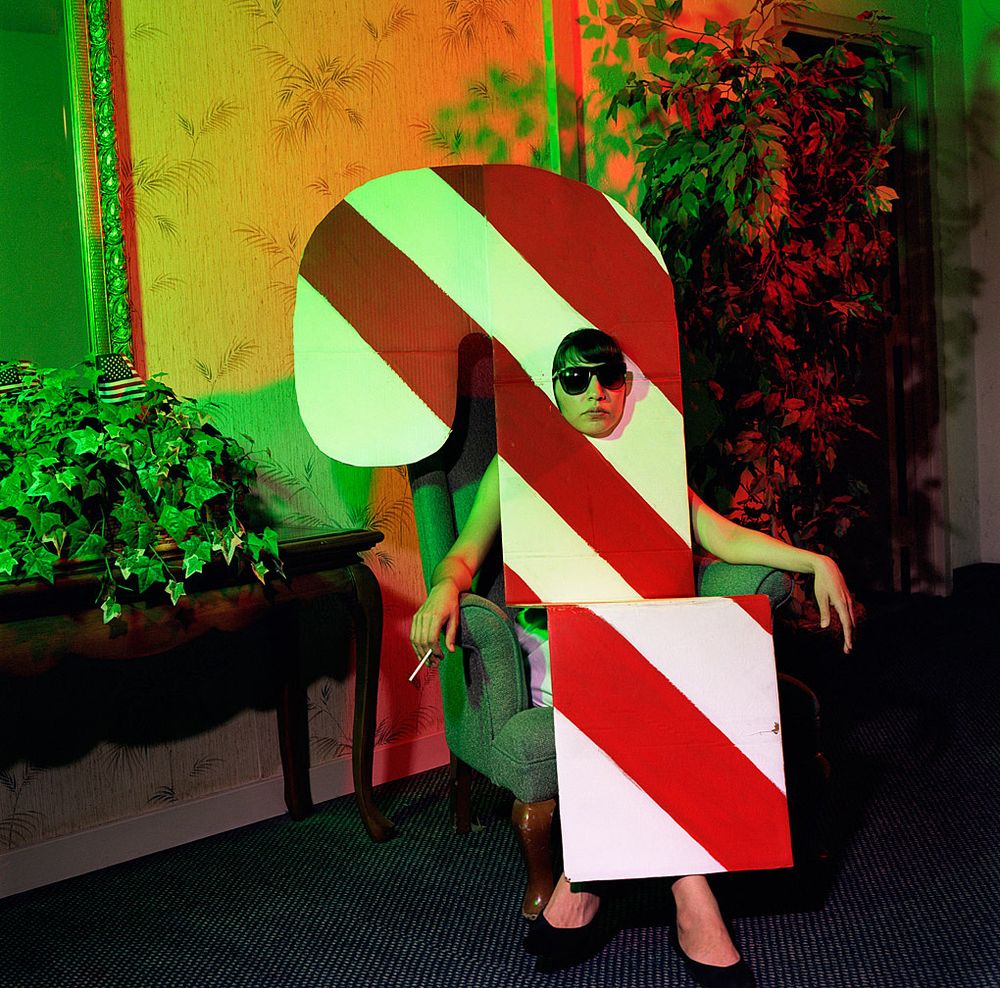 Abstract art installation with diagonal red and white stripes against a green gradient background.