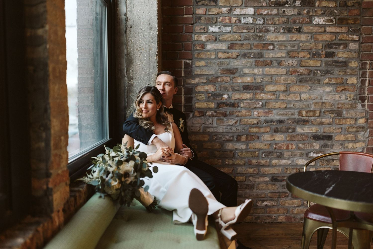 A couple sharing a romantic moment in an industrial brick-walled venue.