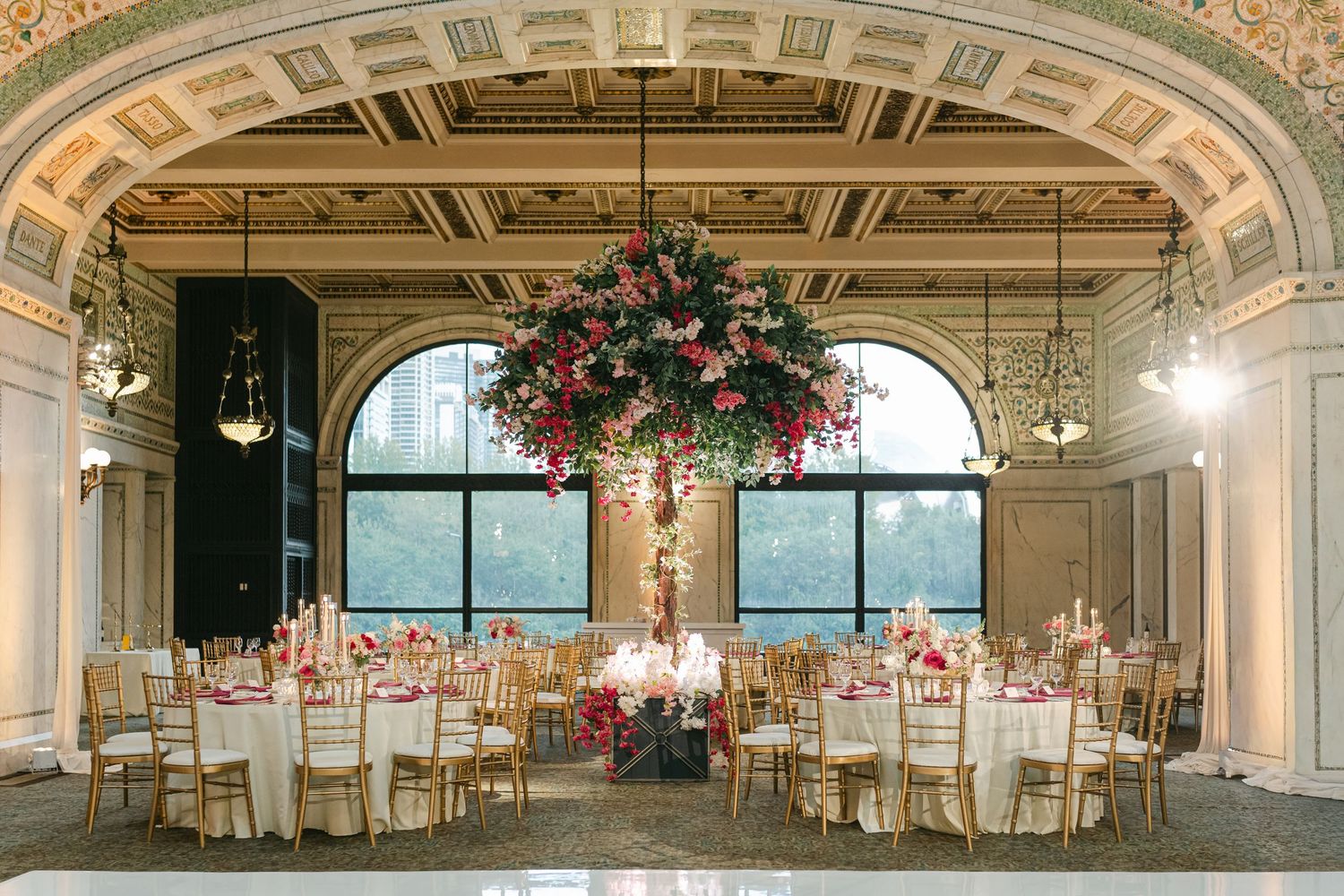 A panoramic view of an elegant wedding reception venue with ornate architecture and floral chandeliers.
