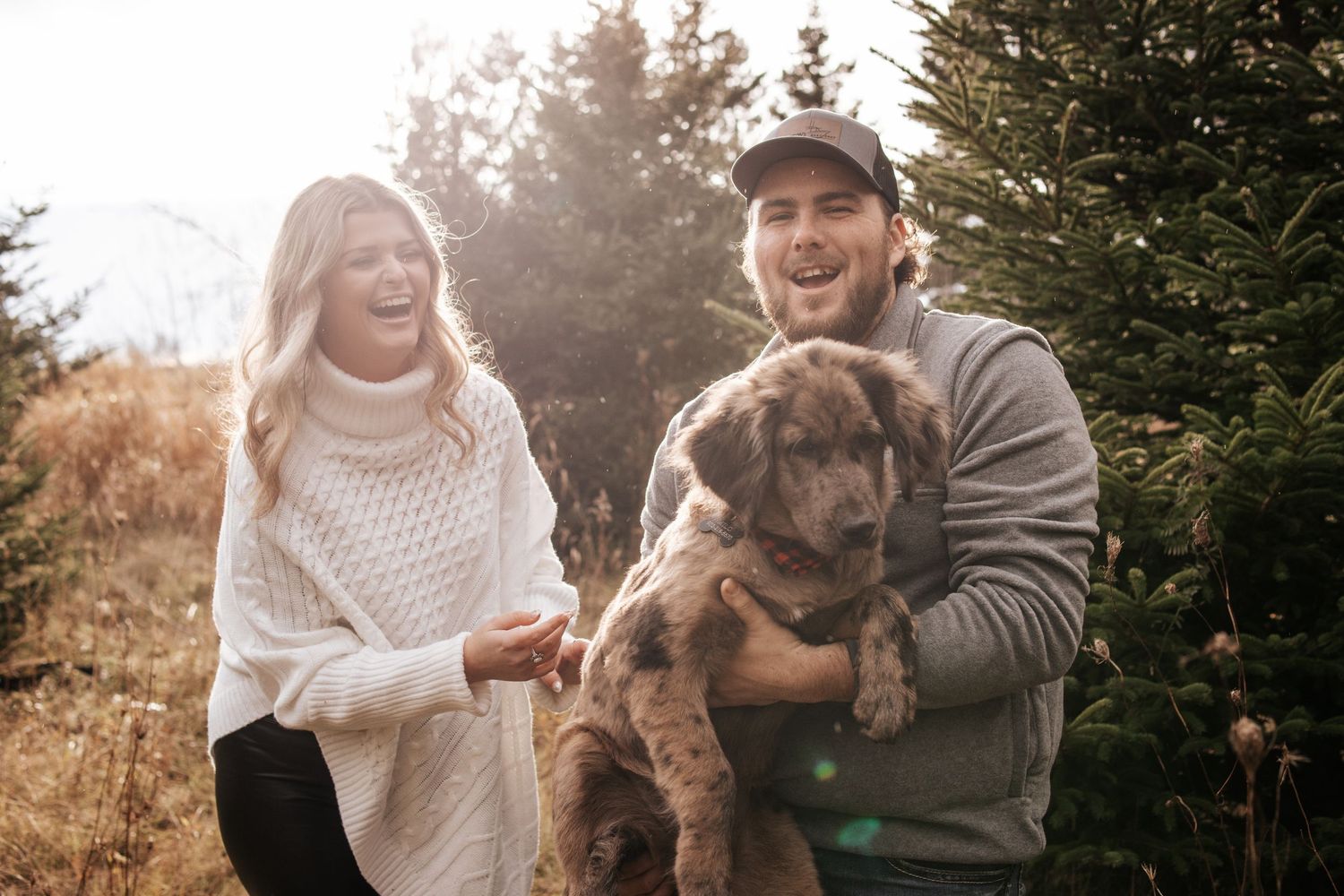 A couple enjoys a playful autumn photoshoot in a park with their adorable French Bulldog puppy.