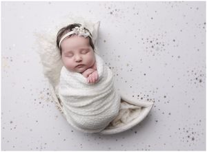 Wrapped newborn baby sleeping on light neutral backdrop in Austin Texas photography studio