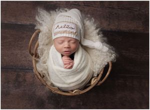 Newborn baby posed in basket with neutral wrap on dark wood backdrop in Austin newborn studio