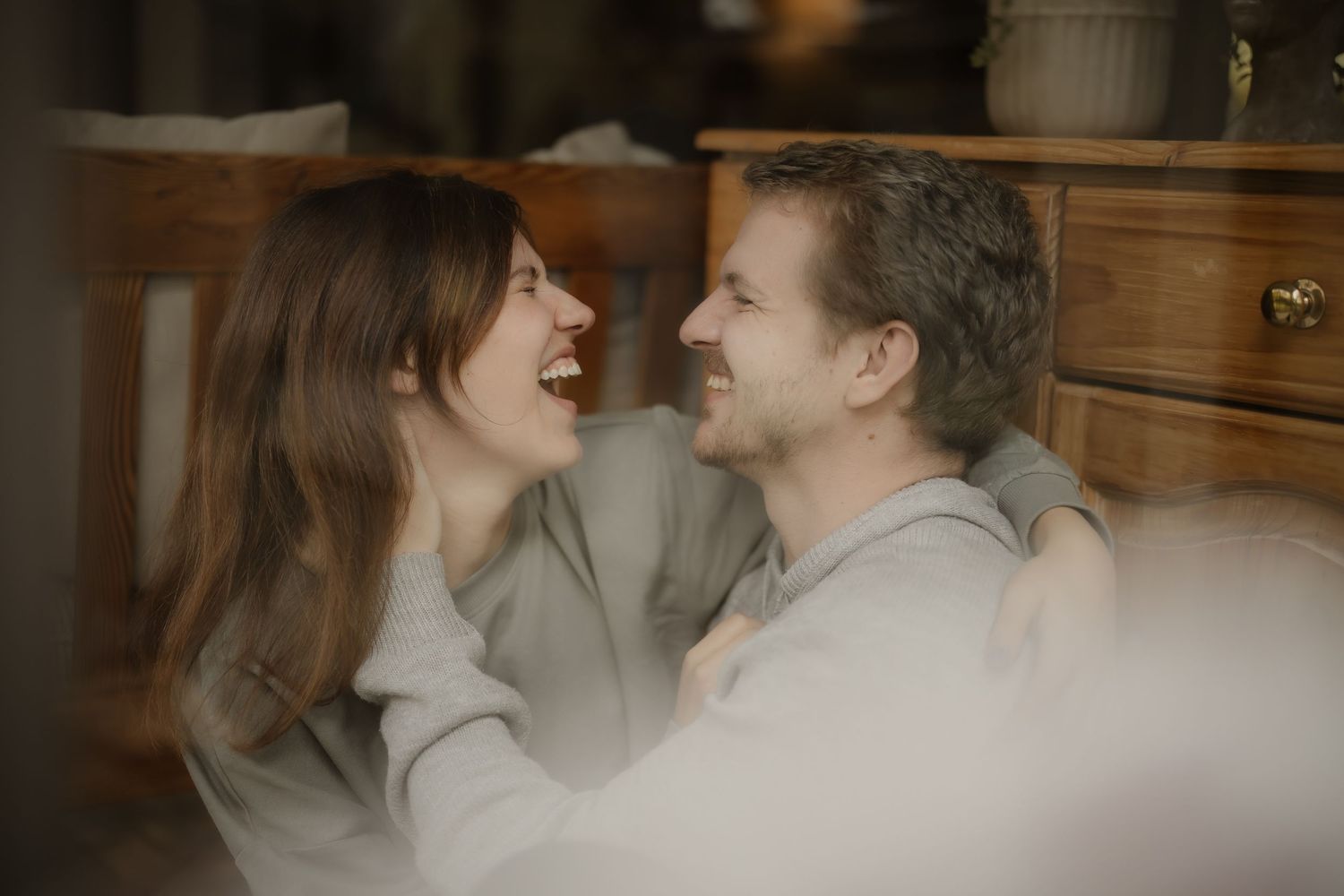 A candid moment of laughter between a couple in a warmly lit interior setting.