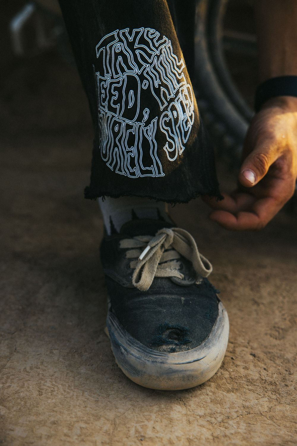 Close-up detail of worn black sneakers with artistic pattern design.