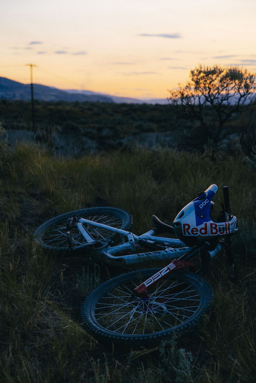 Mountain bike lying on ground during sunset with mountains in background.