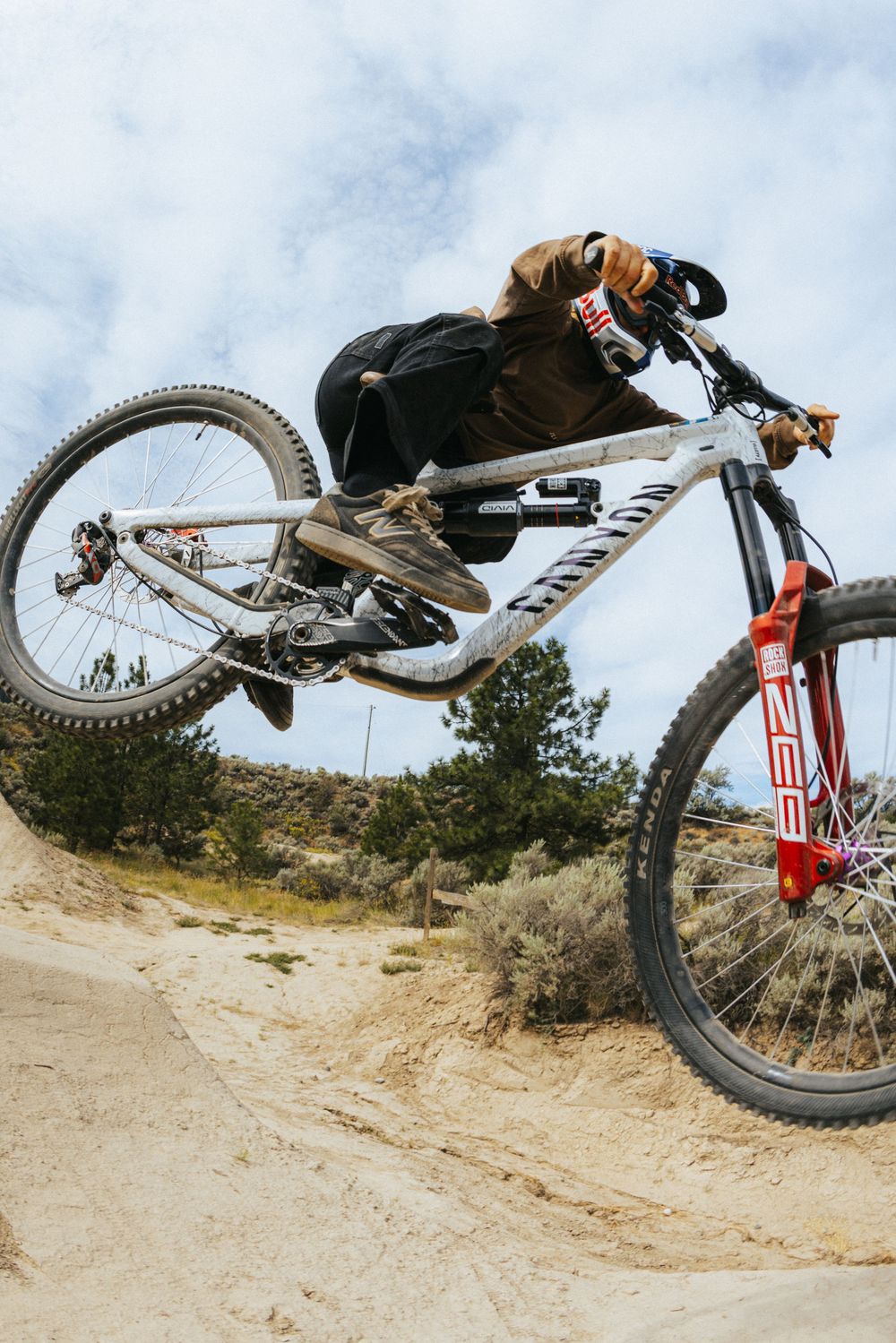 Mountain biker performs aerial trick sequence on dirt trail showing progressive movement through jump.