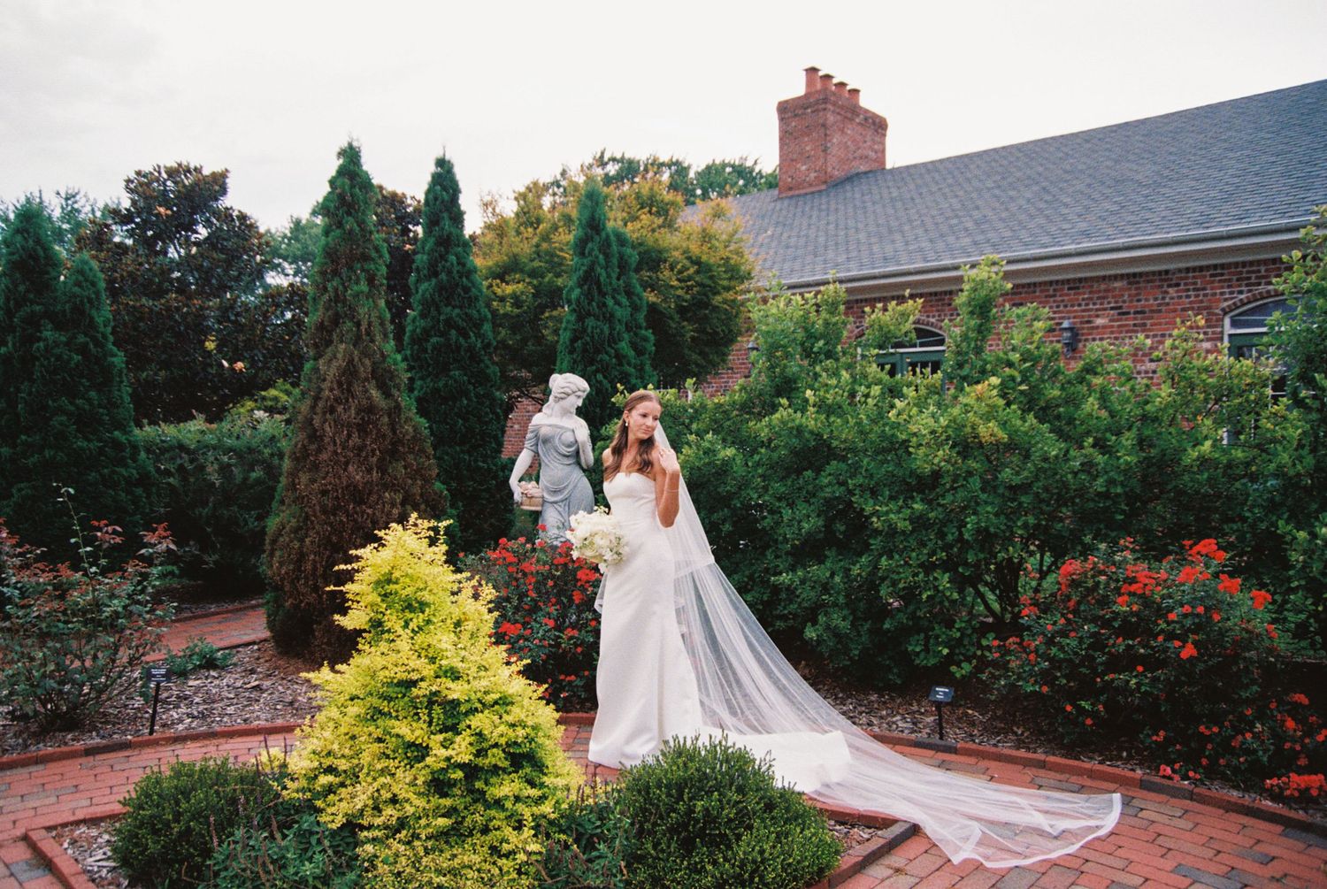 A garden wedding ceremony setting with brick pathways and lush greenery surrounds a couple during their special day.