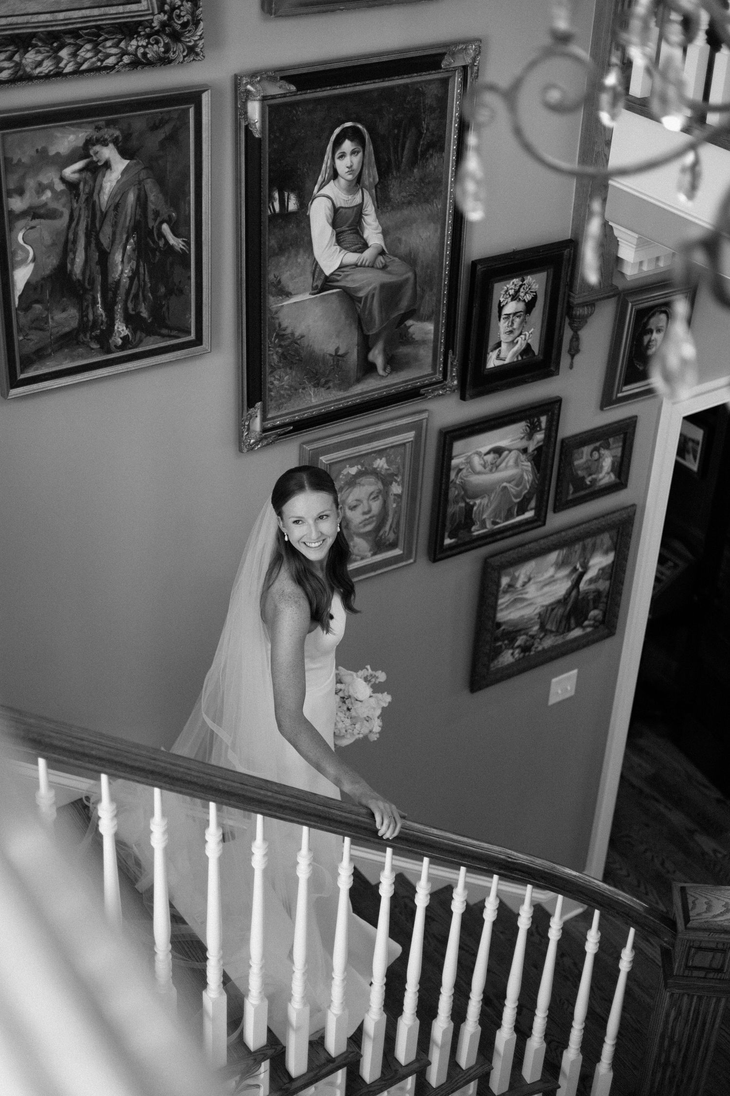 A series of four black and white photos showing someone in a wedding dress descending an elegant staircase with framed art on walls.