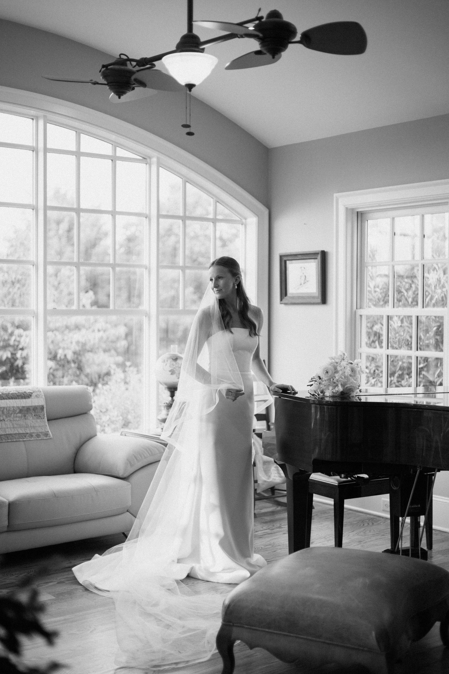 A black and white series of photos showing a wedding dress flowing elegantly in a bright sunlit room with a piano.