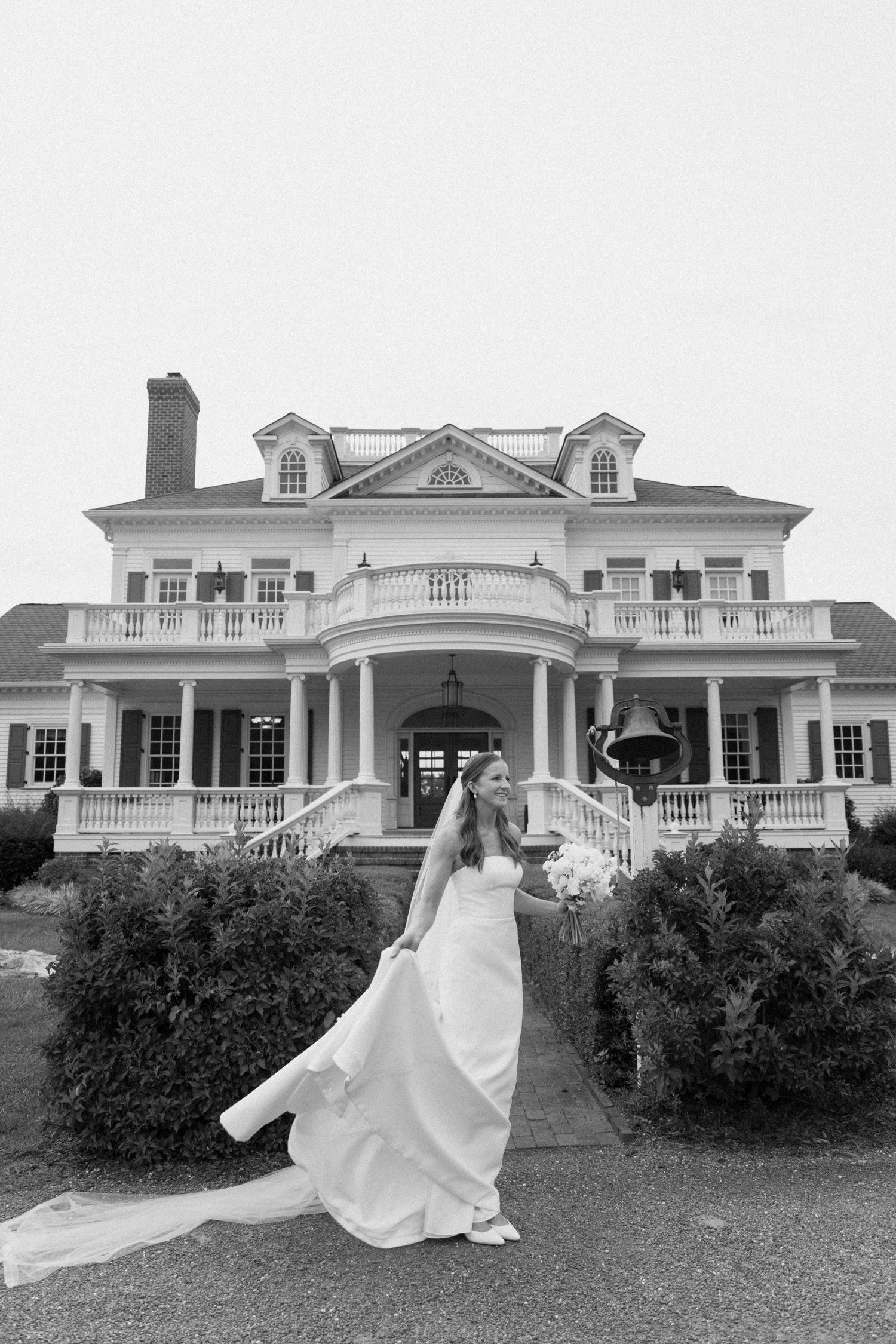 A black and white photo series showing a bride in a flowing gown twirling on the lawn of a grand estate mansion.