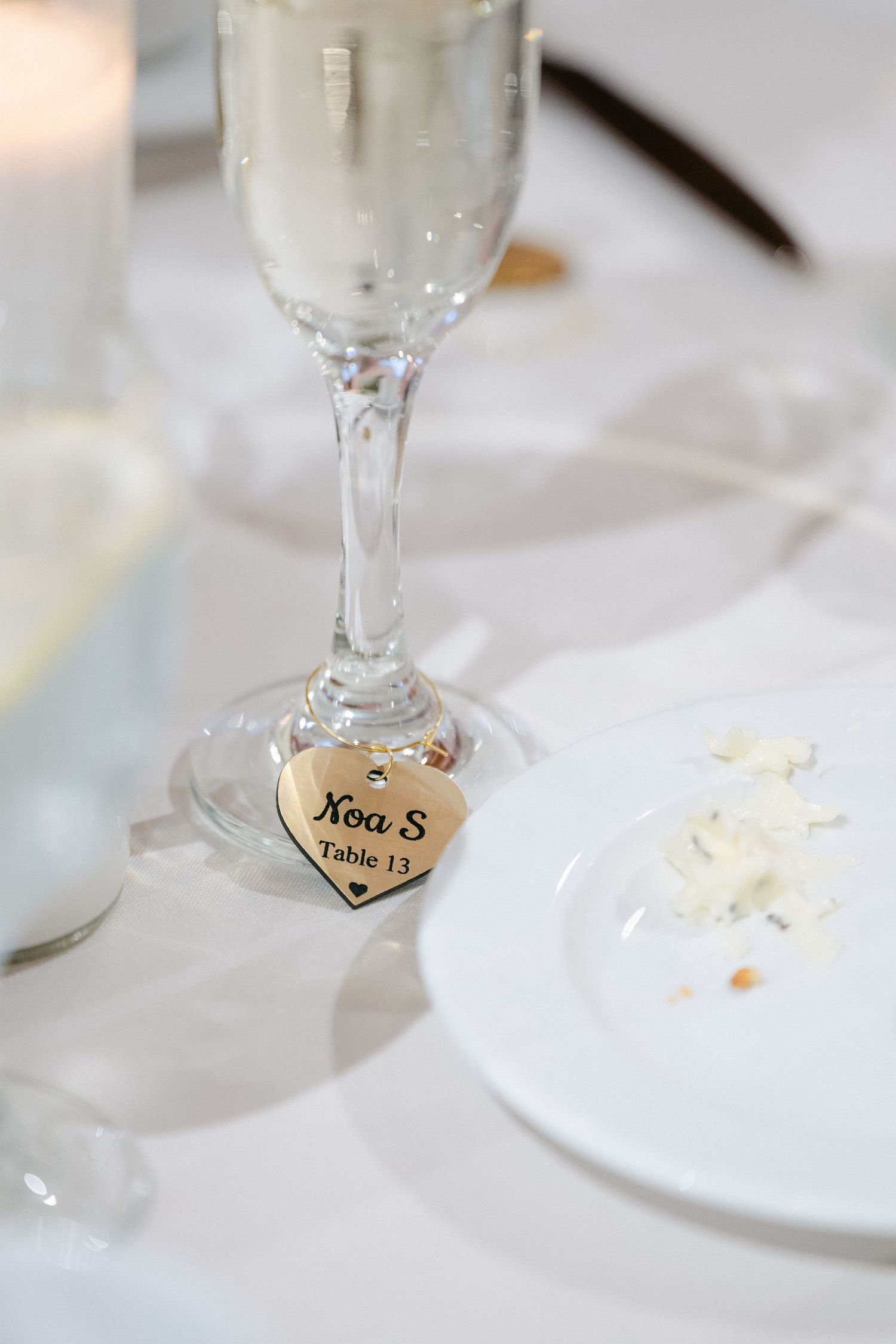 Wine glass charms with handwritten names serve as elegant place settings at a formal table setting.