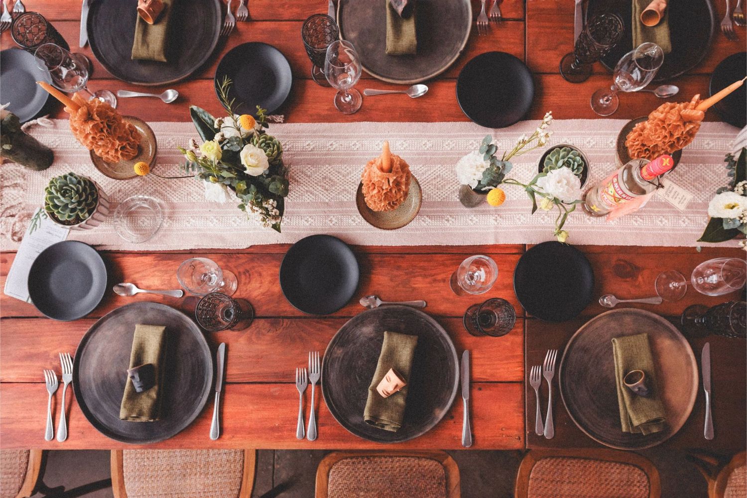Rustic table display of hanging copper and cast iron cookware against red brick wall in restaurant kitchen.