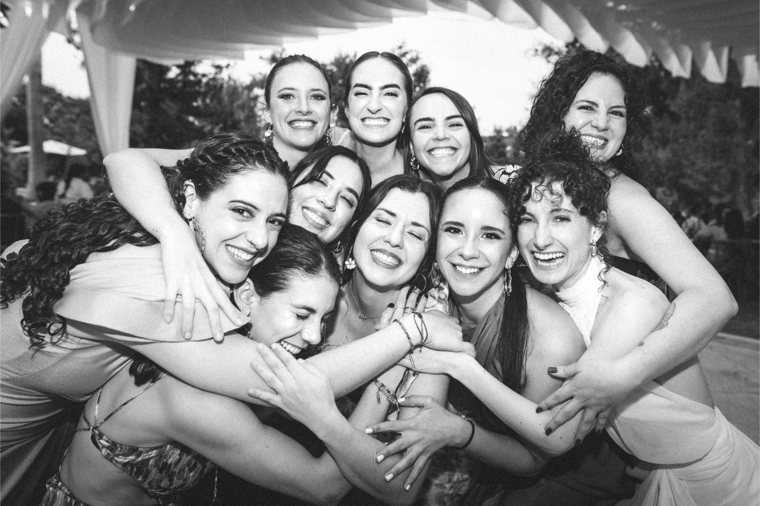Group of people embracing and laughing together in a candid black and white photograph.