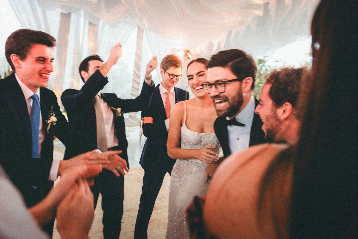 Wedding guests dance and celebrate together on the dance floor during an indoor reception.