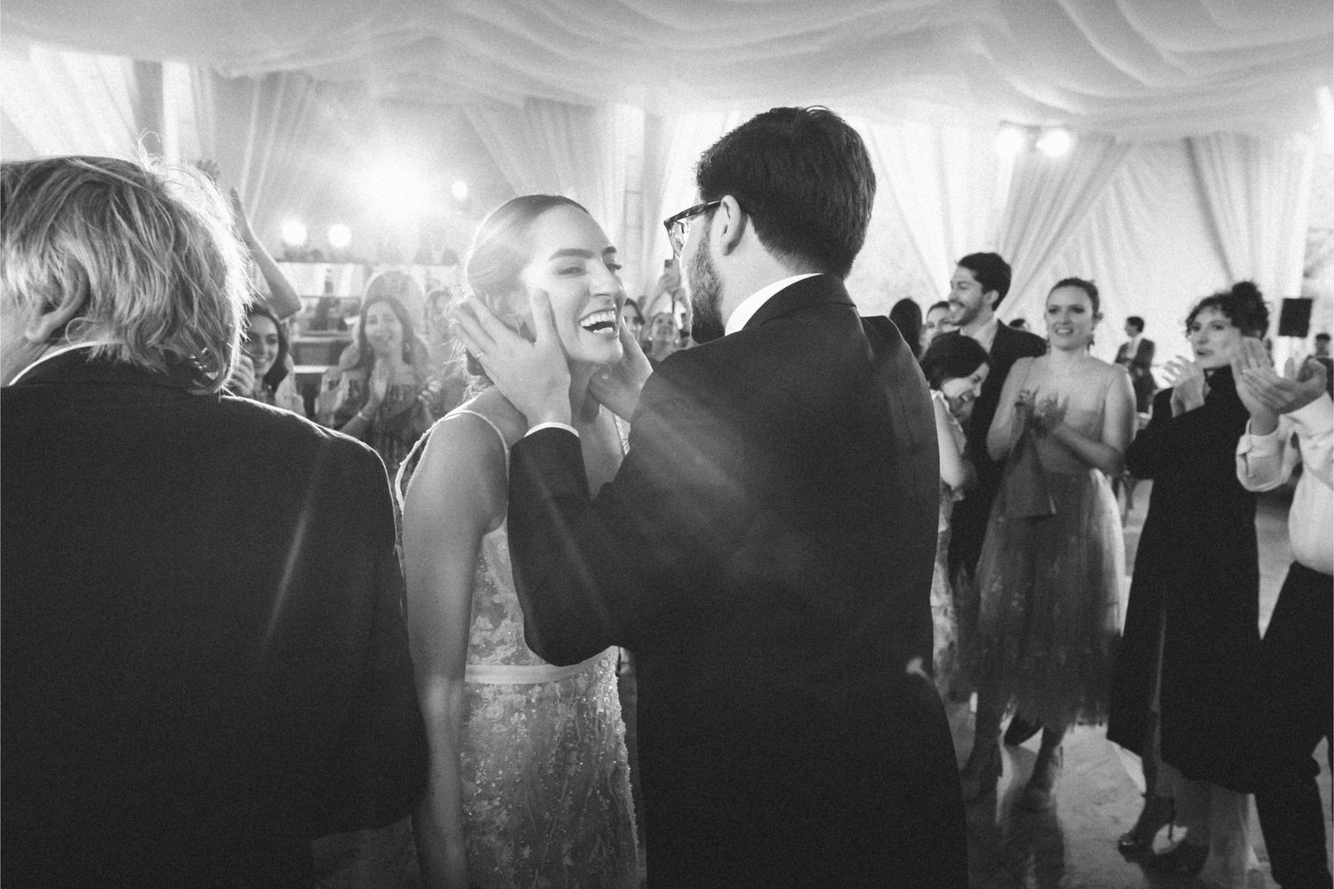 Black and white panoramic view of people dancing and celebrating at a lively wedding reception.