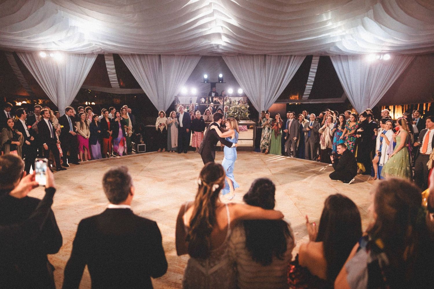 Couples dancing together on an illuminated ballroom floor during an elegant wedding reception celebration.
