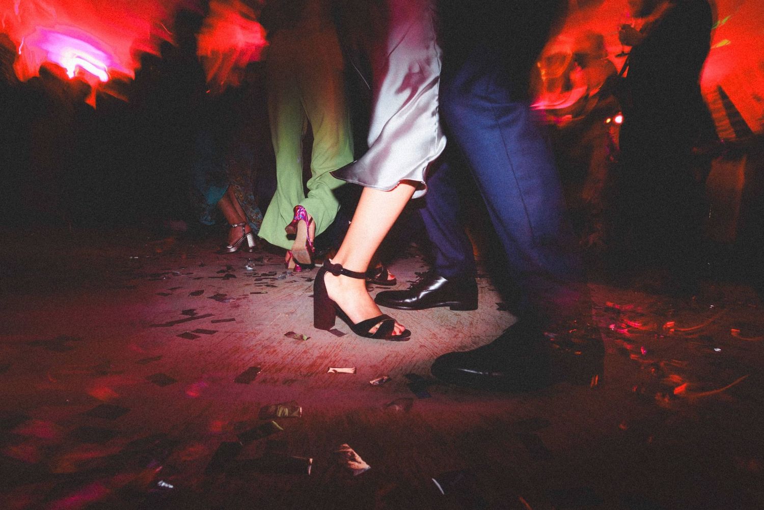 Dance floor lit with dramatic red lighting shows silhouettes of people dancing at a party.