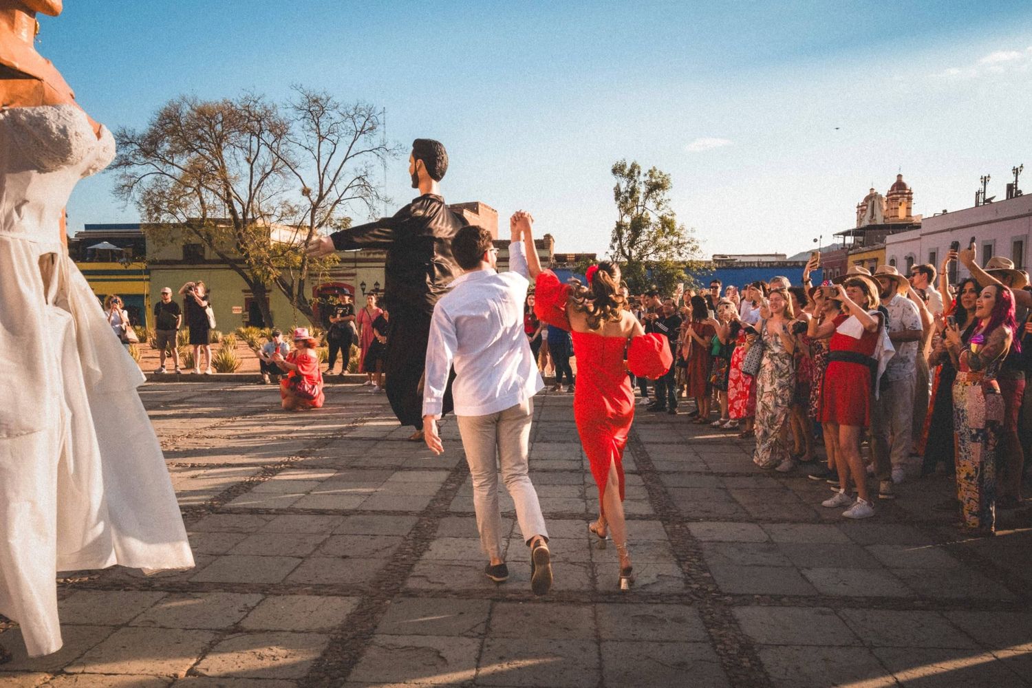A group of people in white and red attire gather at an outdoor event during sunset.